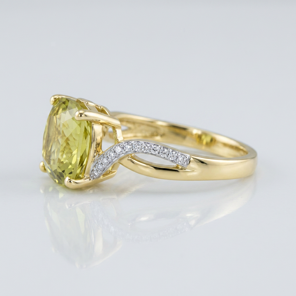 A yellow gold ring featuring a cushion-cut light green gemstone and a curved pavé diamond accent band, set against a clean white background with a soft reflection.