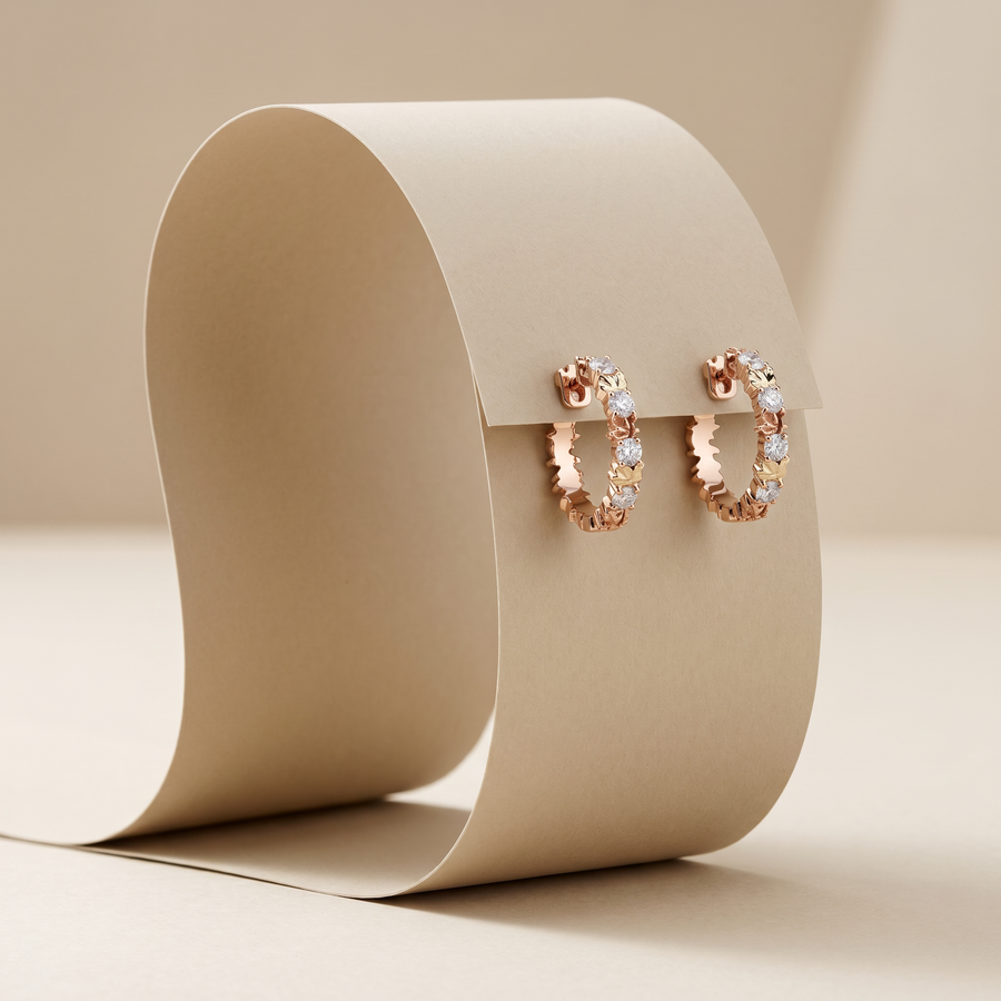 Rose gold hoop earrings with clear gemstones on a beige background